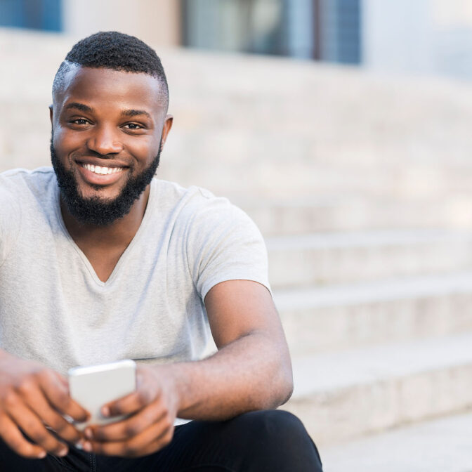 Portrait of casual african guy sitting on stairs and smiling Portrait of casual african guy sitting on stairs and smiling outdoor, copy space